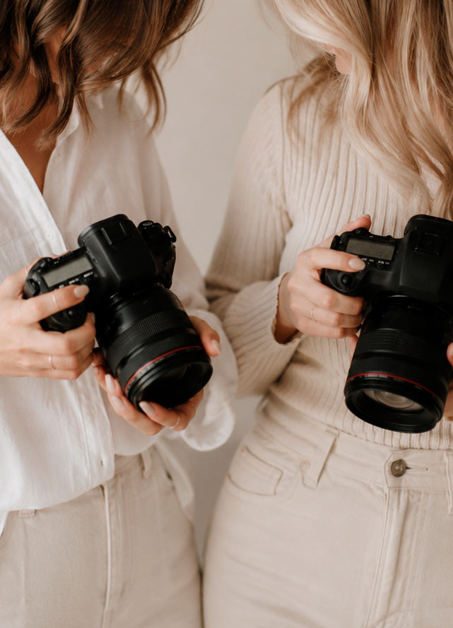 Dos mujeres, una al lado de otra, sujetando una cámara de fotos
